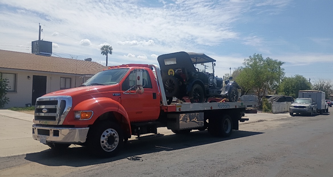 Flatbed tow truck carrying classic vehicle